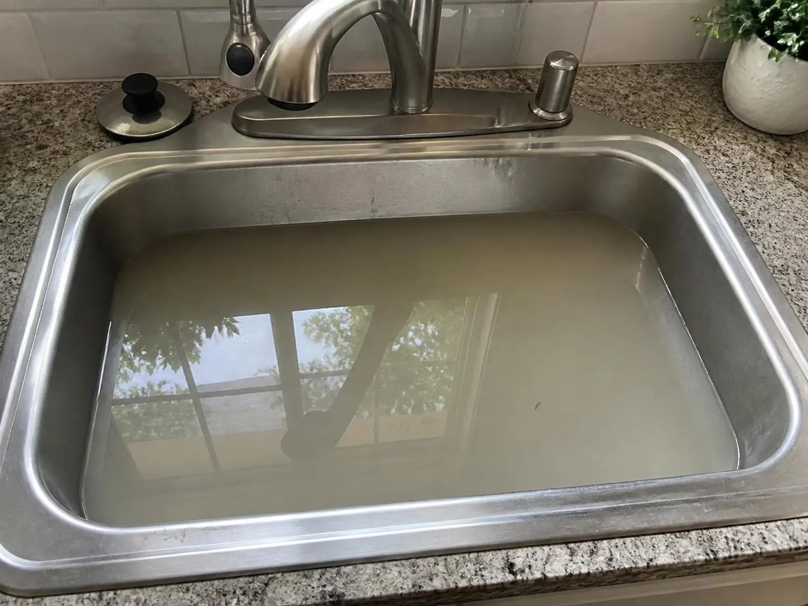 Kitchen sink half full of murky standing water that is not draining